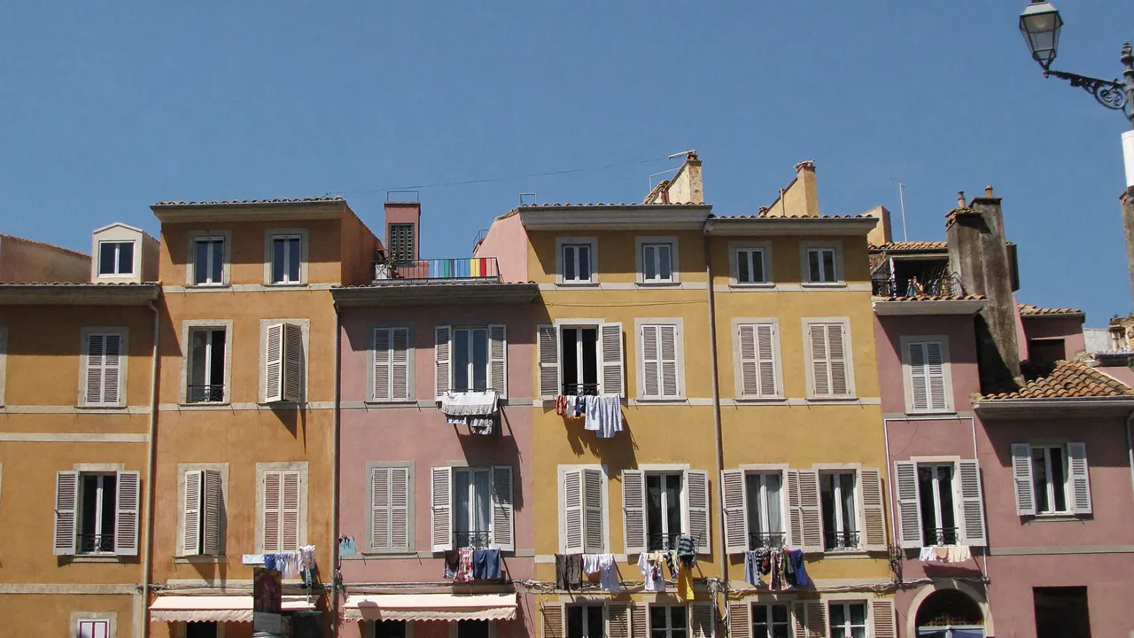 Façades trois-fenêtres ocre et roses avec du linge aux fenêtres dans une rue du Panier à Marseille